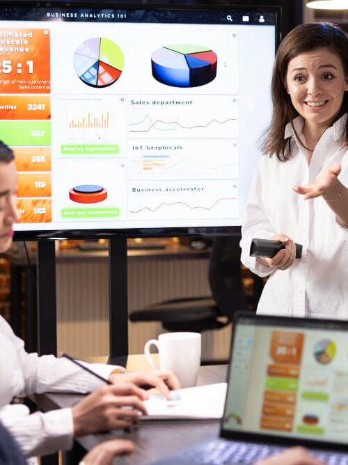 Mulher apresenta painel de dados para colegas de trabalho
