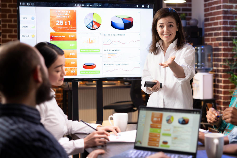 Mulher apresenta painel de dados para colegas de trabalho